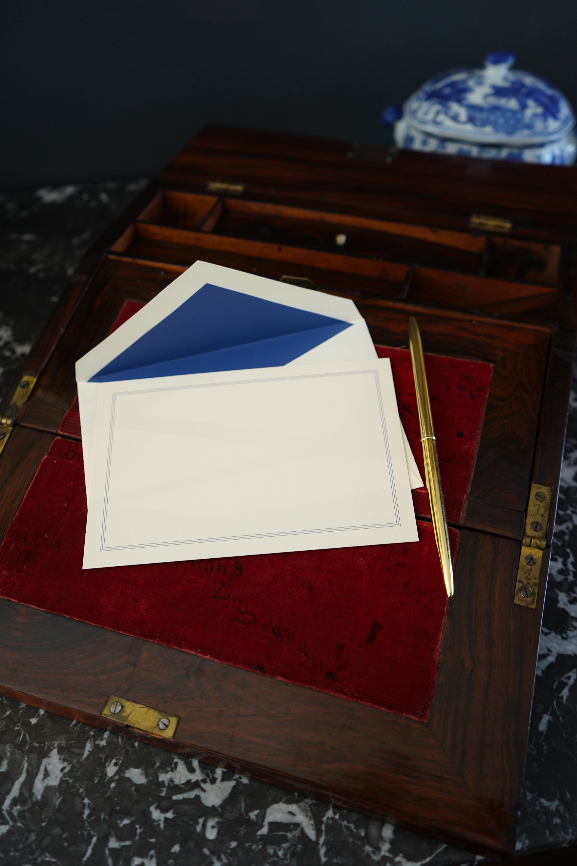 Two cards, one white and one blue, on a red surface with a wooden frame.