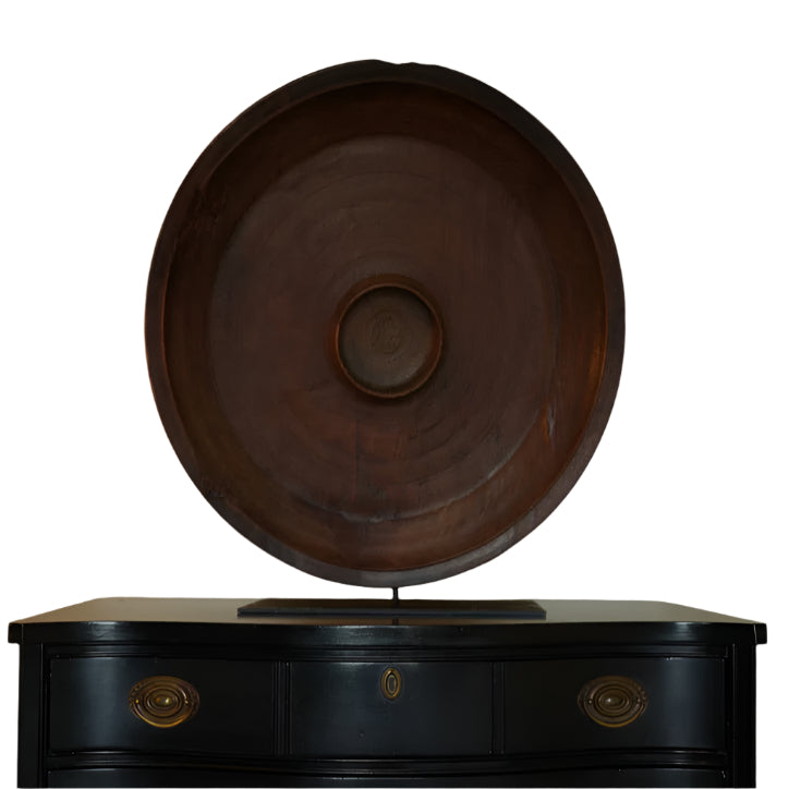 Wooden barrel on a black dresser against a beige wall