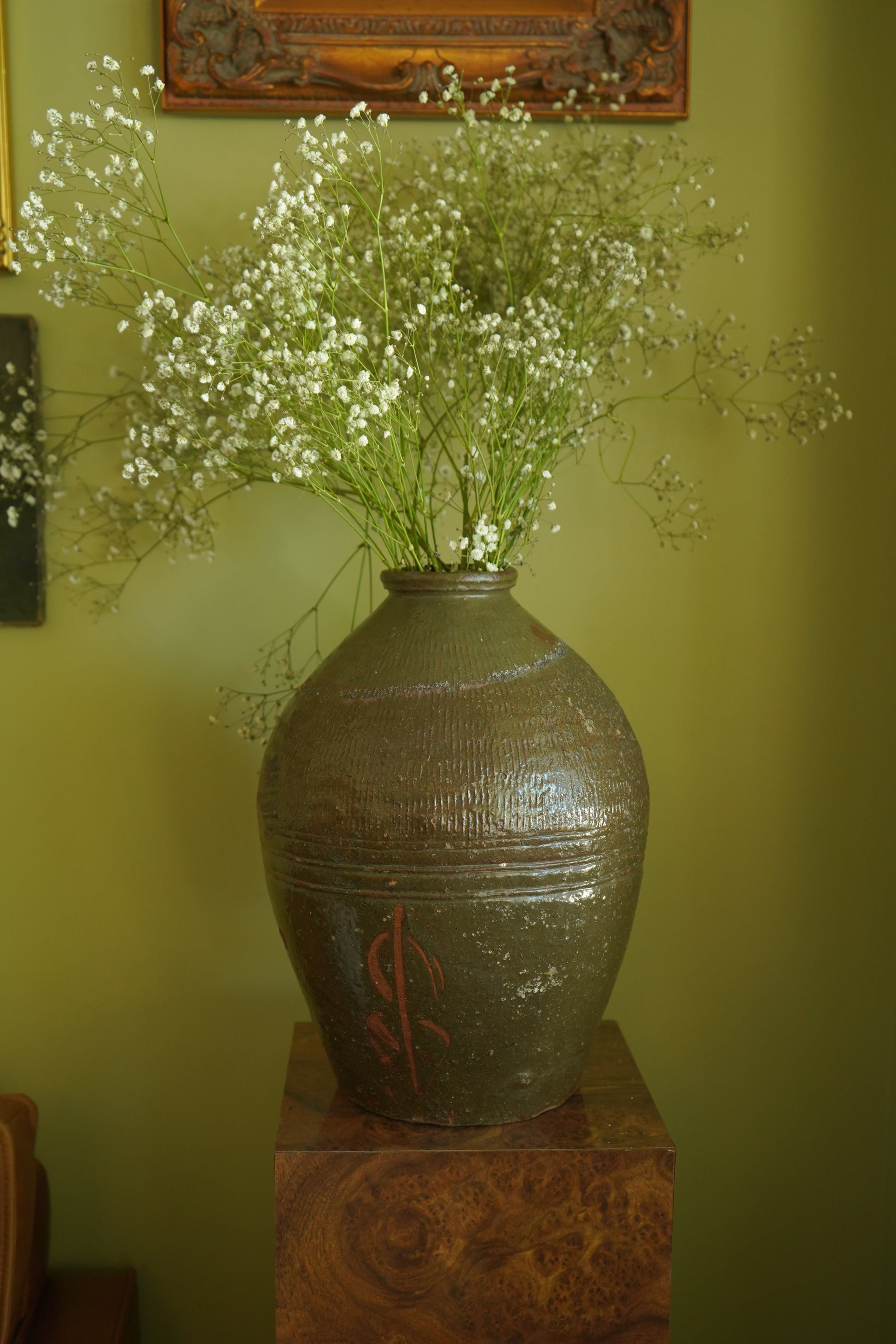 Decorative vase with baby's breath on a green wall