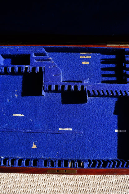 A close-up of a textured blue surface with embossed geometric and architectural shapes, bordered by a reddish-brown edge on the left and a dark area on the right.