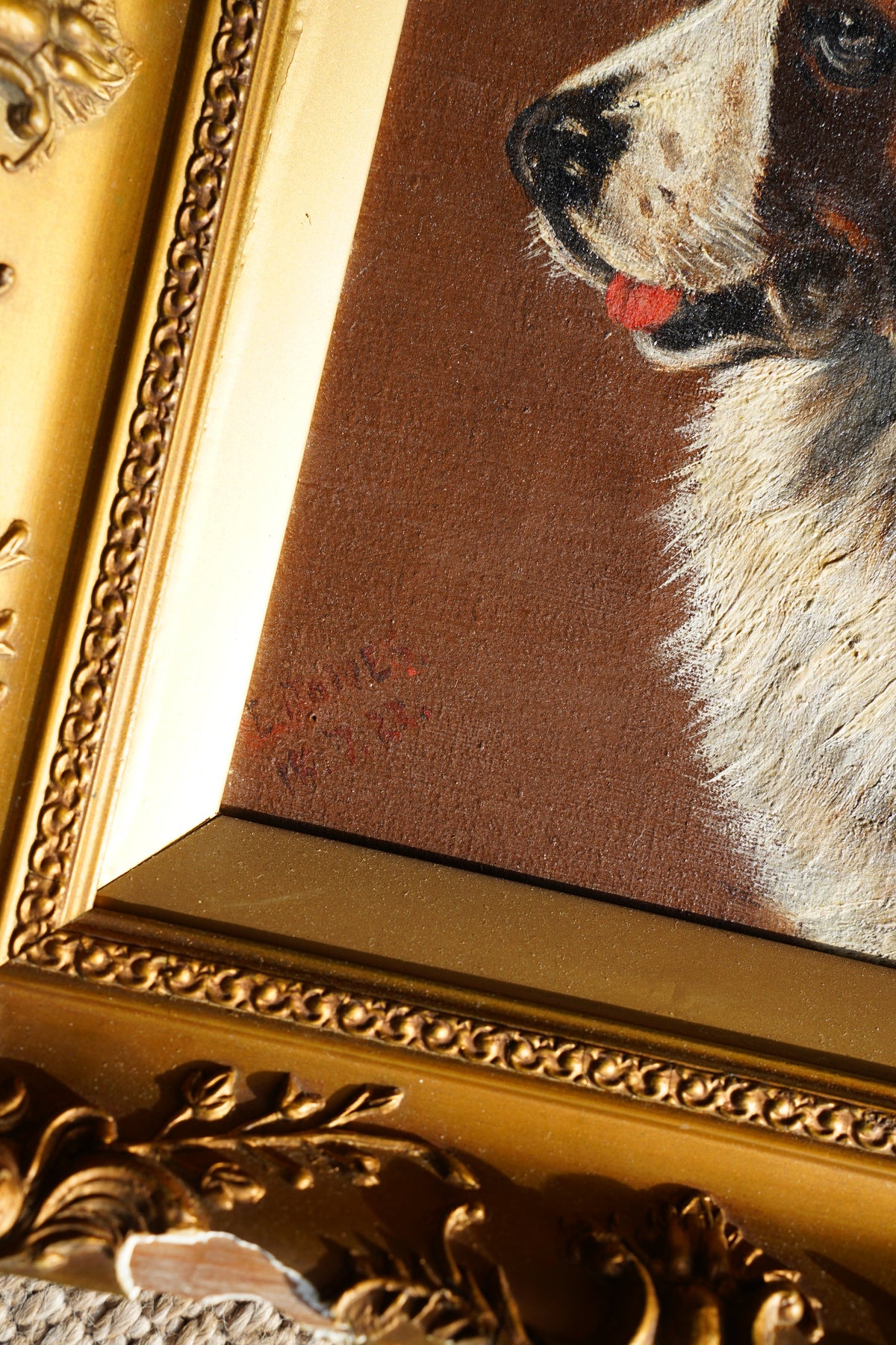 Close-up of an ornate gold picture frame showing part of a painted animal portrait with brown background and white fur details.
